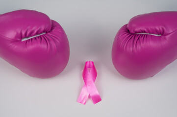 Pink boxing gloves and a pink silk ribbon on a white background. Breast cancer concept. 