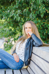 Obraz premium A beautiful fashion young city woman sitting on a bench.Summer,autumn day.Klaipeda,Lithuania.09-02-2022.