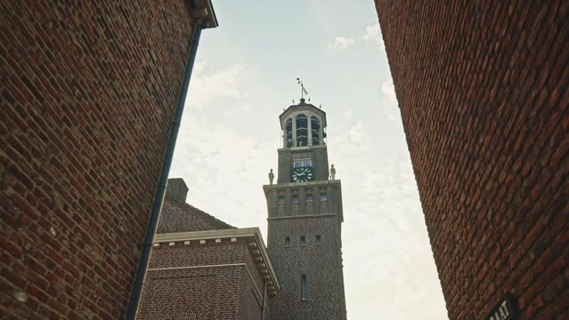 POV shot of a person walking and looking up at the town hall clock tower in the historic fortified town of Heusden, Noord-Brabant, by morning.