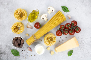 Fototapeta na wymiar Ingredients for cooking pasta, spaghetti, tagliatelle, olives, tomatoes, cheese, olives on a gray background. 