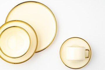 Top-view shot of golden luxury ceramic kitchen utensils on a white background.