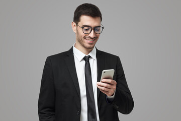 Young successful joyful sales manager typing message on his phone with one hand