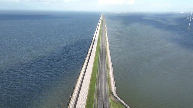 The Afsluitdijk flood defense system in the Netherlands between North Holland and Friesland closing the IJsselmeer off from the Wadden Sea. Dam and road infrastructure aerial drone view.