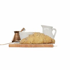 Closeup of delicious croissants, coffee cup, milk jug, cezve and a spoon of sugar on a wooden board