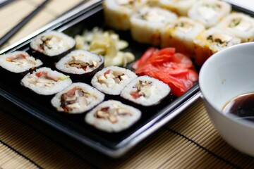 Close up of red ginger rolls with a soy sauce bowl on a bamboo mat - perfect for a Japanese concept
