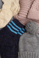 Knitted winter clothes, neatly stacked on a white background. The surface of women's woolen things, textiles. Close-up knitted texture. The background is gray. Casual clothes.