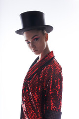 Profile portrait of a beautiful young woman with makeup wear in a bright glitter costume and top hat, white background.