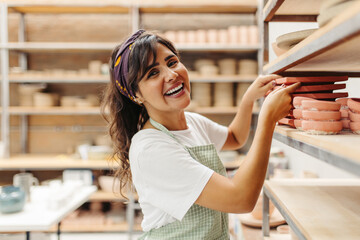 Young craftswoman smiling at the camera in her ceramic shop