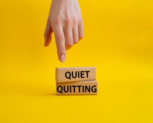 Quiet quitting symbol. Concept word Quiet quitting on wooden blocks. Beautiful yellow background. Businessman hand. Business and Quiet quitting concept. Copy space.