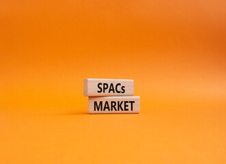 SPACs market symbol. Concept words SPACs market - special purpose acquisition companies market - on wooden blocks. Beautiful orange background. Business concept. Copy space.