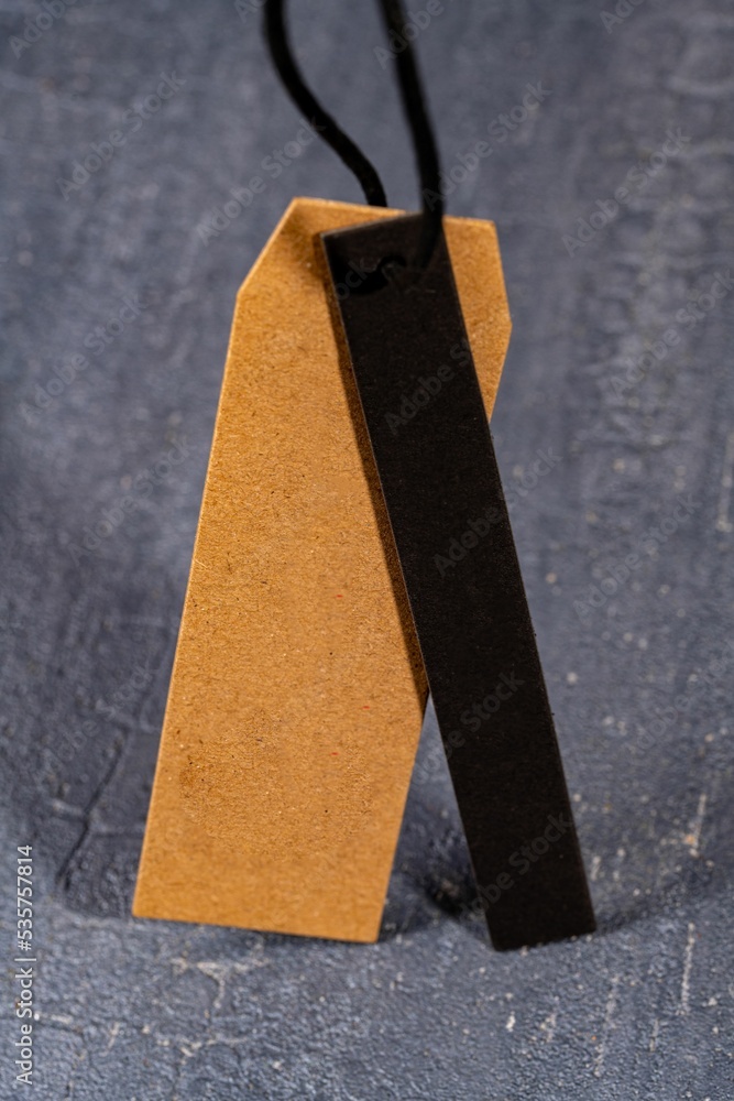 Poster vertical shot of a brown paper tag on a string with a thin black strip of cloth