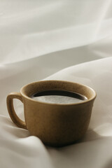 cup of coffee in the morning. espresso coffee. Coffee porridge on a white background
a cup of coffee on a white cloth. sun rays on a cup of coffee