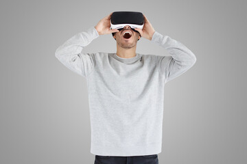 Astonished young man experiencing virtual reality while using VR headset for entertaining