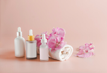 Obraz na płótnie Canvas Beauty products setting with towel, cosmetic bottles and orchid flowers at pink background