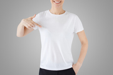 No face photo of woman pointing at her blank white t-shirt with finger on gray background