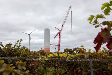 Building and assembling a construction windturbine by crane. Farmland with construction work at the Wind farm in the middle of a vineyard. Energy saving concept from wind turbine construction