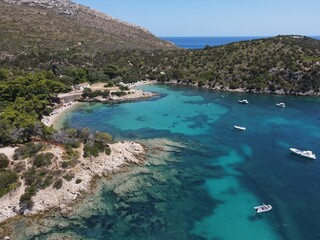 Aerial view of Cala Moresca and Figarolo Island in Golfo Aranci, north Sardinia. Birds eye from above of yacht, boats, crystalline and turquoise water. Tavolara Island in the background, Sardegna.