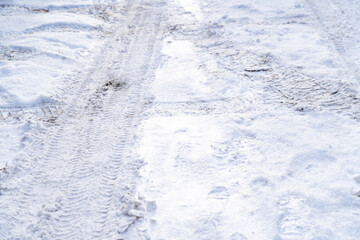 Texture of white winter country road, tire tracks and shoe prints in snow