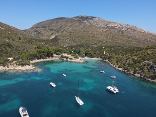 Aerial view of Cala Moresca and Figarolo Island in Golfo Aranci, north Sardinia. Birds eye from above of yacht, boats, crystalline and turquoise water. Tavolara Island in the background, Sardegna.