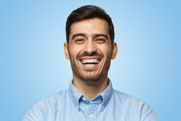 Portrait of handsome laughing business man, isolated on blue