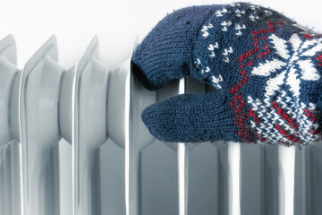 hand in winter mittens is warming near the heater winter heating season concept