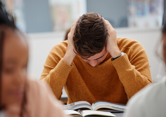 University, study and tired student reading book in class while studying for test or exam. Education, stress and burnout man with headache, knowledge and scholarship learning college work in library.