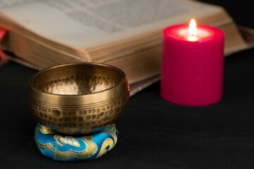 Closeup of Tibetan bell with an old spiritual book and red candle