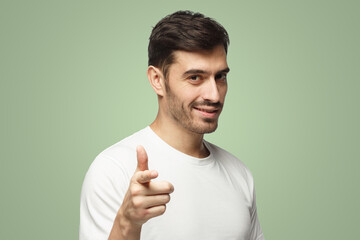Caucasian male pointing at camera on green background