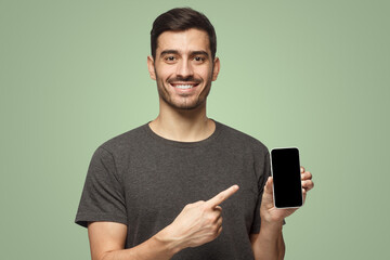 Happy man demonstrating blank smartphone and pointing to empty screen with smile
