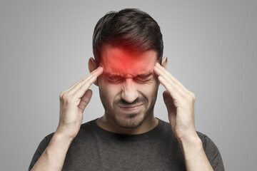 Portrait of man suffering from severe headache, pressing fingers to temples with closed eyes