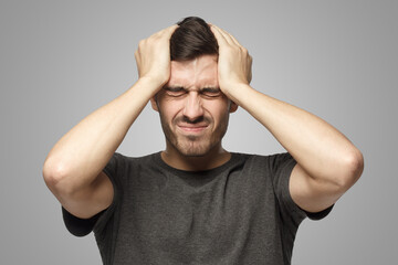 Man showing how much head hurts, experiencing pain, looking miserable and exhausted