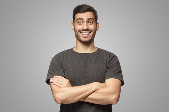 Portrait of laughing handsome man in gray t-shirt standing with crossed arms