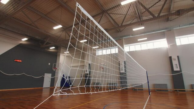 Volleyball net above empty field in sports school gym closeup. Equipment for team ball games in athletic center