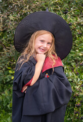 Halloween. A girl in a robe and hat. A little sorceress in the costume 