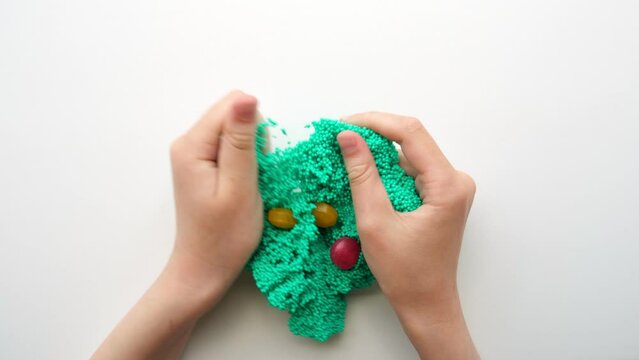 Hands Playing with textured slime with bubbles, stretching the gooey substance. Female teen hand holding green shining slime, squeezing it. Adorable Girl stretching slime toy to the sides. Liquid toy.