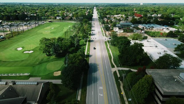 Aerial drone top shot over a long highway with cars passing by beside the Golf club in Northbrook Illinois, USA on a sunny day.