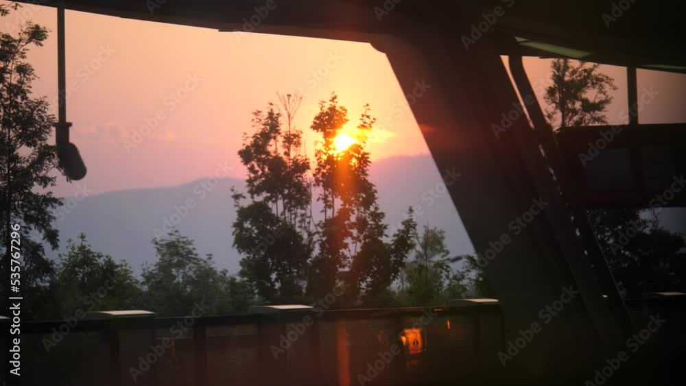 Poster sunset view behind trees from train window in china. 4k videos. slow motion.