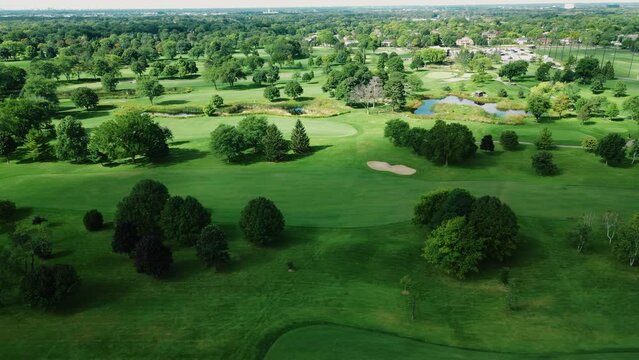 Aerial drone rotating shot over golf club covered with lush green grasslands along with small ponds with fountains on a cloudy day in Northbrook Illinois, USA.