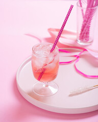 Pink cocktail with ice on a pink background