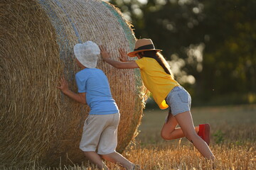 Children roll hay across the field © Oksana