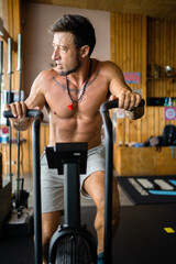 Fototapeta na wymiar Vertical photo of a man using an airbike in a gym