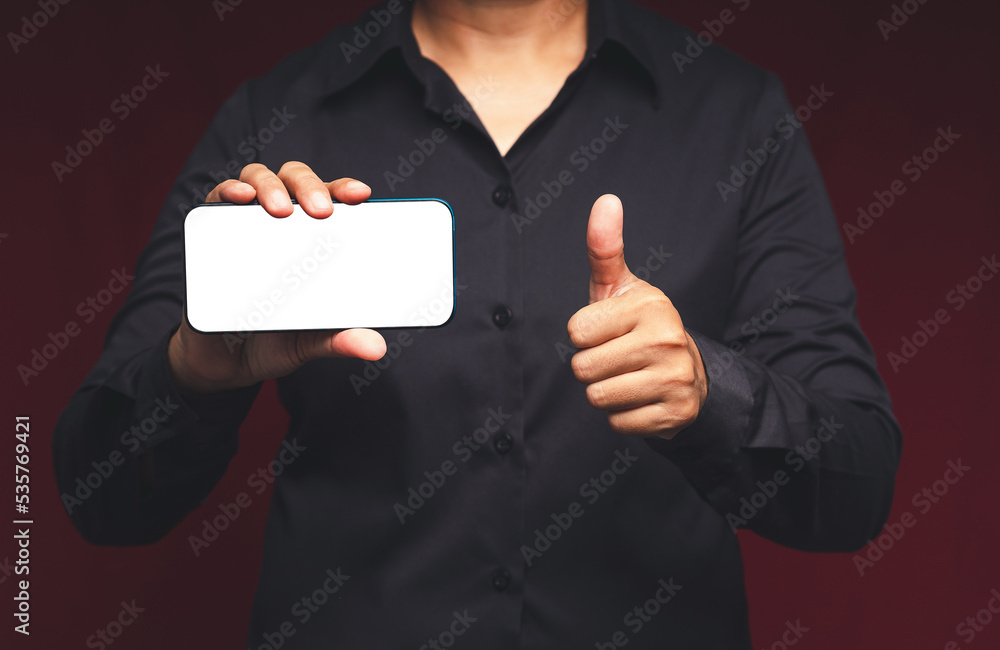 Poster a businessman holding a horizontal mobile phone with a blank white screen and showing thumbs up whil