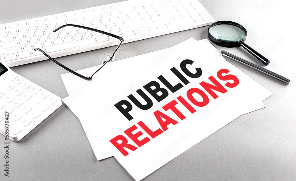 Aufkleber public relations text on a paper with keyboard, calculator on grey background