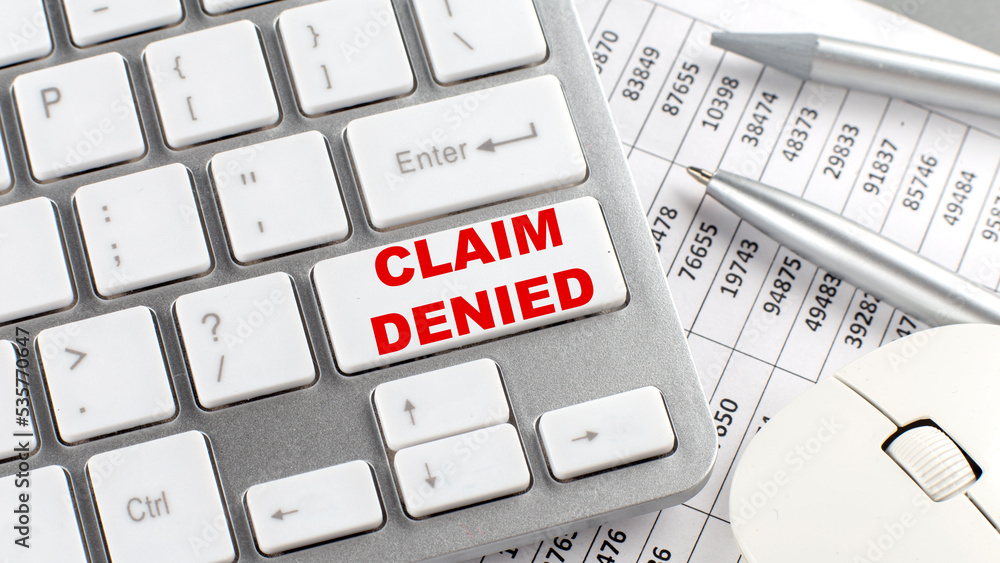 Poster claim denied text on a keyboard wirh chart and pencil