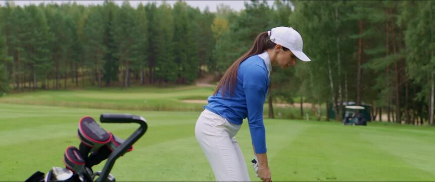 MED Caucasian female playing golf, striking a ball during the course. Shot with 2x anamorphic lens