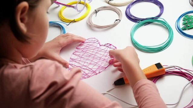 Teen Girl Using 3d Pen. Printing with Colored Plastic Wire Filament. Child making a Heart, drawing with 3D pen. Artwork, Robotics. STEAM, STEM education. Modern Technologies. Play and study at home
