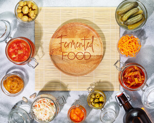 Probiotic food. Pickled or fermented products. Fermented vegetables and mushrooms in glass jars, bottle with home made beer, around empty wooden plate with inscription fermented food. Home preserving
