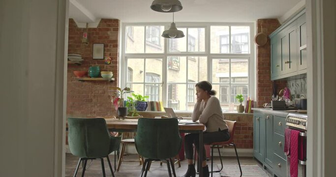 Young Adult Female at Home Paying Bills, Home Finance on Laptop in Kitchen