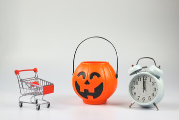 Halloween pumpkin bucket  with shopping cart and white vintage alarm clock 12 pm. isolated  on...