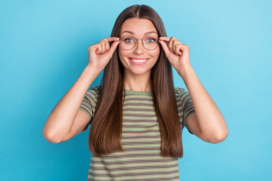 Photo of adorable positive glad girl with straight hairdo dressed striped t-shirt fingers touch eyewear isolated on blue color background